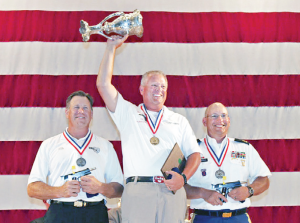 Brian Zins, center, waves his trophy from the gold medal position on the winner's stand at the National Matches, with silver medalist John Zurek on the left, and SFC James Henderson, bronze medalist, on the right