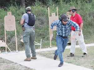 Students doing the Tueller Drill. They start back to back at three yards. The student on the right starts to sprint to see how far he can get before the other student can draw and fire. Steve North is the range officer.