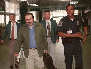 Justice Scalia has the smile of a successful hunter as he is escorted through the Jackson International Airport by US Marshalls and an airport police officer on April 3, 1997. Scalia bagged a 20-pound turkey while hunting with friends near Hattiesburg, MS. (Chris Todd/ The Clarion-Ledger via AP)