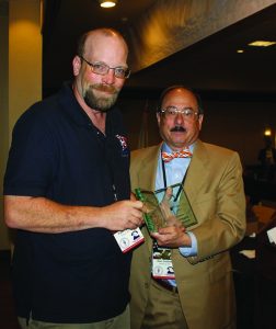 Paul Lathrop (left) receives the first annual award for excellence in social media, named for the late Ray Carter, an SAF staffer, from Alan M. Gottlieb.