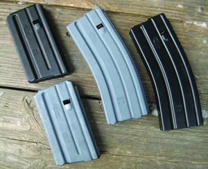 The grey magazines are the traditional military hard surface anodized finish with the Mil-Spec dry lube finish. The black mags have the PTFE finish.