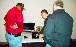 Lieutenants Joe Barnes and Dave Case get feedback on their shooting techniques provided by the MantisX sensor device displayed on Austin Allgaier ‘s tablet.