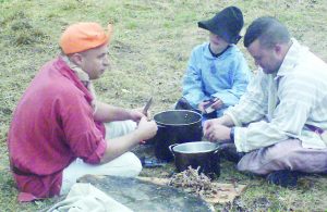 Lucas Fulmer, center, with his Uncle Mark to his left and his Dad to the right helps prepare the Squirrel Stew.